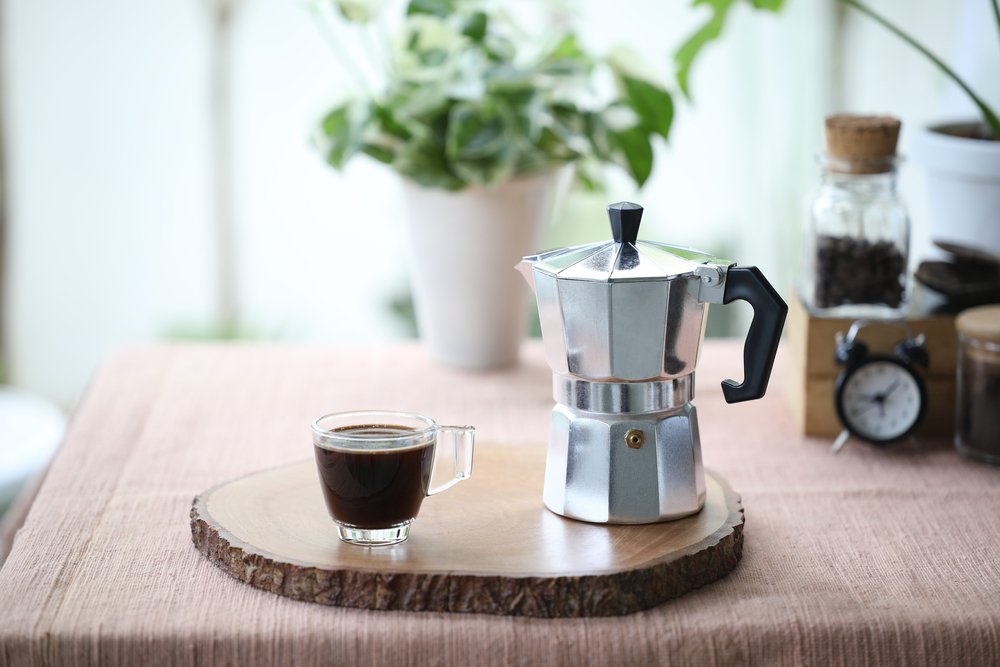 Moka koťogo kávovary, konvičky - kávovar a šálek s kávou na dřevěné podložce