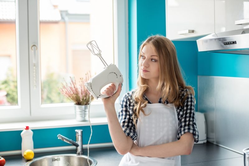 žena drží ručný mixér v kuchyni