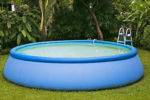Modrý kruhový bazén so schodíkmi na záhrade