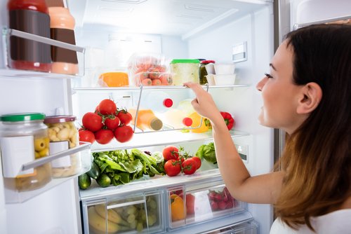 Mladá žena si vyberá jedlo z chladničky