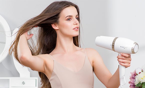 Žena si suší vlasy fénom Wellneo 2v1 AirPro 
