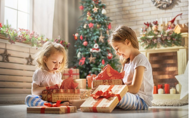Dve dievčatká si rozbaľujú vianočné darčeky