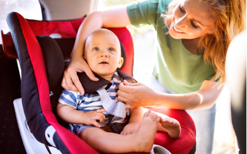 Žena zapína dieťa v autosedačke