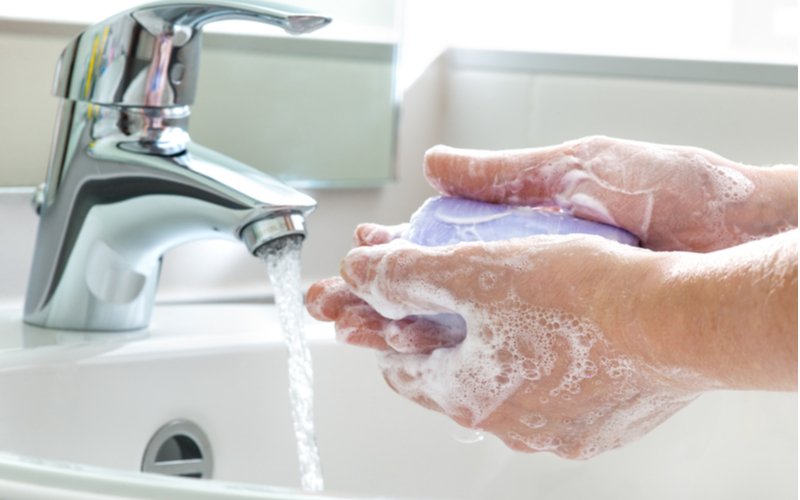 Umývanie rúk fialovým mydlom a prúd tečúcej vody