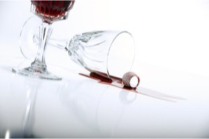 prevrhnutý pohár s červeným vínom