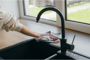 žena utierajúca vodu okolo kuchynského drezu