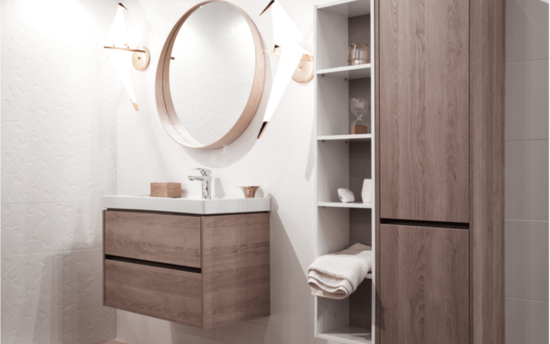 kúpeľňa s bielymi obkladačkami a závesnými skrinkami s dekorom tmavého dreva