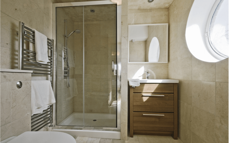 kúpeľňa so svetlohnedým obkladom a závesnou skrinkou so zrkadlom