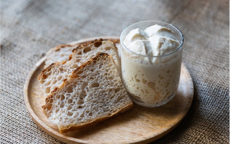pšeničný kvások lievito madre v pohári, krajce kváskového bieleho chleba
