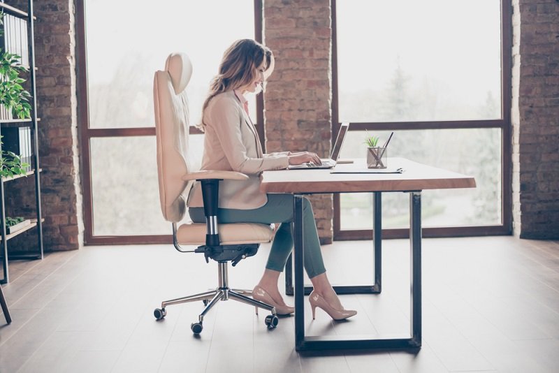 Mladá žena na stoličke pracuje na notebooku.